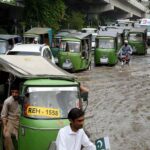Vehicles passing through stagnant rain water accumulated at Suray Pull Chowk after heavy rain in the city