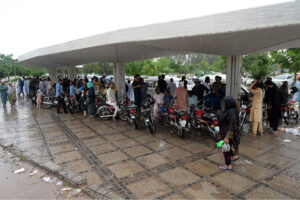 Female students wait for their college bus during a downpour in the Federal Capital