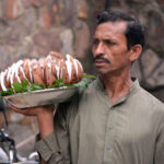 A street vendor selling decorated coconuts on a tray to attract passers-by on Jail Road in the city