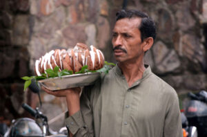 A street vendor selling decorated coconuts on a tray to attract passers-by on Jail Road in the city