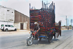 A tricycle holder on the way with heavy load of traditional beds (Charpai)