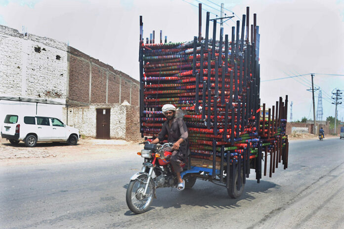 A tricycle holder on the way with heavy load of traditional beds (Charpai)