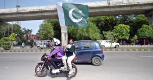 A woman wearing skating shoes is holding a national flag as she travels along Murree Road, as the nation starts preparations to celebrate the upcoming Independence Day in a befitting manner.