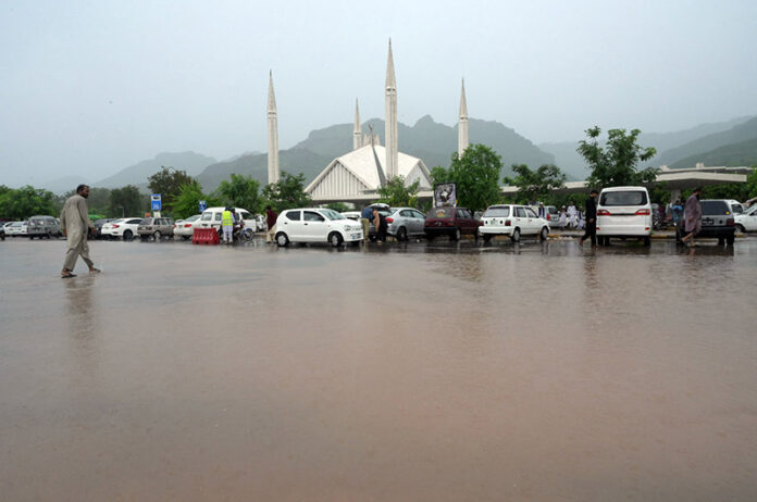 Female students wait for their college bus during a downpour in the Federal Capital