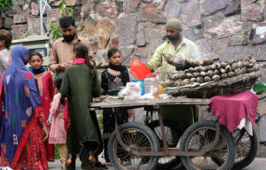 A street vendor selling decorated coconuts on a tray to attract passers-by on Jail Road in the city