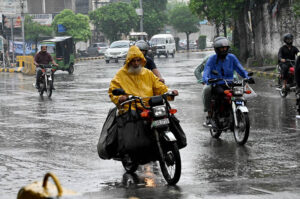 A woman holding an umbrella to protect from rain while sitting rear seat of motorcycle in the Provincial Capital.