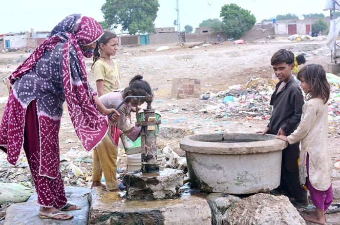 A woman and her children fill their pots with water from a hand pump at Norani Basti on the outskirts of the city