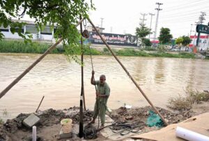 A labourer busy boring for hand pump at canal bank near Khushab road.