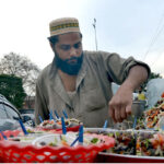 A street vendor draws the attention of customers near the railway station with a tray of zesty Alochana Chaat, enhanced with colors, spicy chili and sour flavors