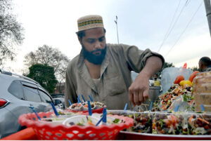 A street vendor draws the attention of customers near the railway station with a tray of zesty Alochana Chaat, enhanced with colors, spicy chili and sour flavors