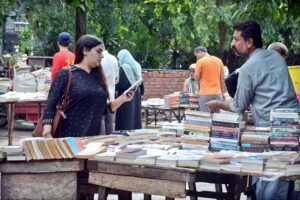 Woman busy in selecting and purchasing old books from roadside stall at Mall Road in Provincial Capital.