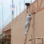 Workers painting the wall of flyover at Kalma Chowk