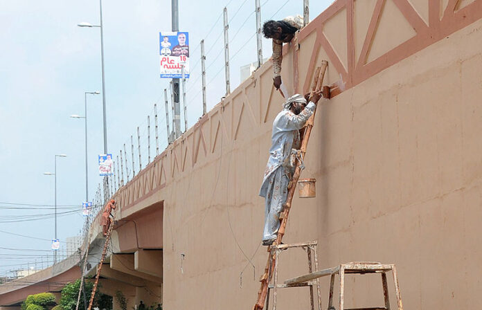 Workers painting the wall of flyover at Kalma Chowk