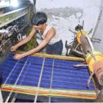 A worker is busy operating a power loom to prepare cloth in a local factory