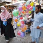 An elderly man selling illuminated balloons at Shafi Bazar attracts customers to support his daily livelihood