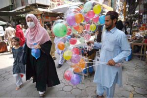 An elderly man selling illuminated balloons at Shafi Bazar attracts customers to support his daily livelihood