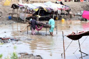 Gypsy people take out their belongings from rain-soaked huts near Miro Khan Road.