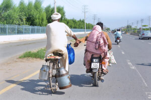 An elderly person on bicycle is holding the hand of a motorcyclist to reach his destination