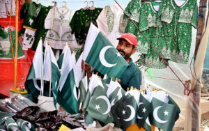 A motorcyclist fixing national flag on his bike after purchasing from vendor in connection with upcoming Independence Day celebrations.
