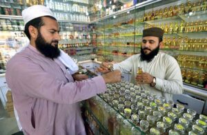 A vendor filling glass bottle with local perfume ‘ittar’ for the customer at Hashtnagri area