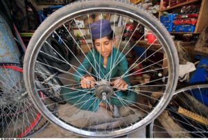 A young mechanic busy repairing bicycle tyre at his workplace, Sikandar Pura.