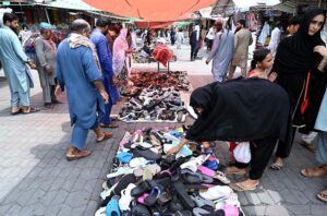 Customers busy in selecting and purchasing secondhand stylish shoes from a makeshift stall at H-9 weekly bazaar in Federal Capital.