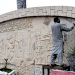 A skilled worker restores the intricate mural painting on the wall at Kachhari Chowk, bringing historical art back to life
