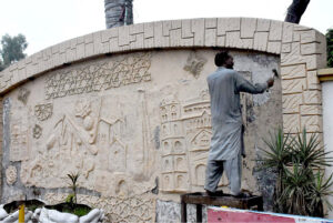 A skilled worker restores the intricate mural painting on the wall at Kachhari Chowk, bringing historical art back to life