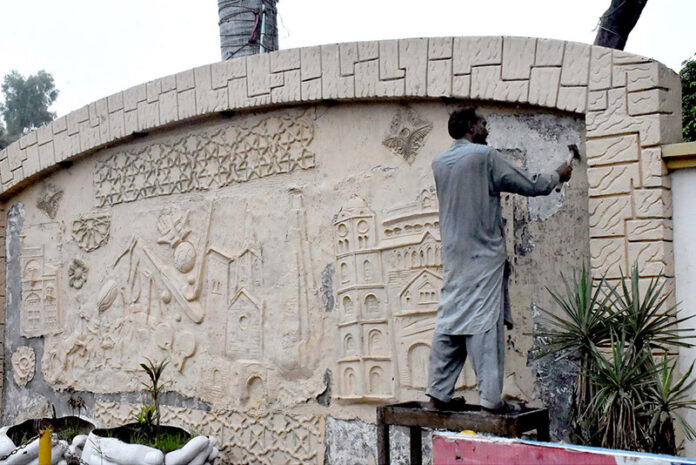 A skilled worker restores the intricate mural painting on the wall at Kachhari Chowk, bringing historical art back to life