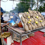 Vendor displaying roasted sweet potatoes (Shakarkandi) to attract the customers in city