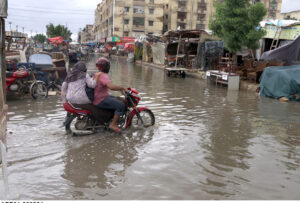 A motorcyclist navigating through a flooded road on Main Road in Scheme 33 near Fariya Chowk during the monsoon season in the Provincial Capital.