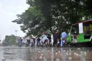 A young motorcyclist, drinking water while riding without a license plate during monsoon rain, is at high risk of causing an accident due to their disregard for traffic laws and unsafe behavio.