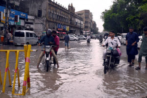 Vehicular traffic moves accumulated rain water on a Tower area during monsoon rain in the metropolitan.