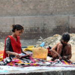 Gypsy girls washing clothes while sitting by a local canal