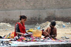 Gypsy girls washing clothes while sitting by a local canal