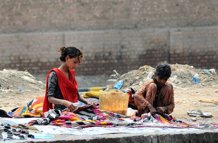 Gypsy girls washing clothes while sitting by a local canal