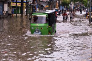 A rickshaw driver steers through accumulated rainwater at Lakshmi Chowk in the Provincial Capital.