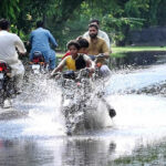 After heavy rains in the provincial capital, young motorcyclists are splashing water all around while passing through the water