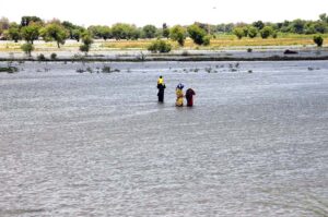 Flood affected people of Ali Nawaz Siyal village taluka Gambat passing through flood water to safer place in flood hit area of Indus River near Larkana-Khairpur Road.