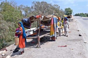 Flood affected people of Ali Nawaz Siyal village taluka Gambat passing through flood water to safer place in flood hit area of Indus River near Larkana-Khairpur Road.