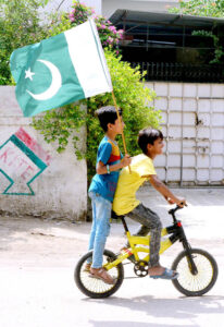 Youngsters riding bicycles with national flags to express their love while celebrating Independence Day at Latifabad.