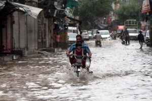 People ride a horse cart through a flooded road during rain that experienced in Provincial Capital.