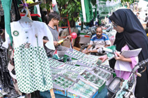 A woman carefully selecting and purchasing national flags, badges, and other celebratory items as the nation gears up to celebrate Independence Day in befitting manners.