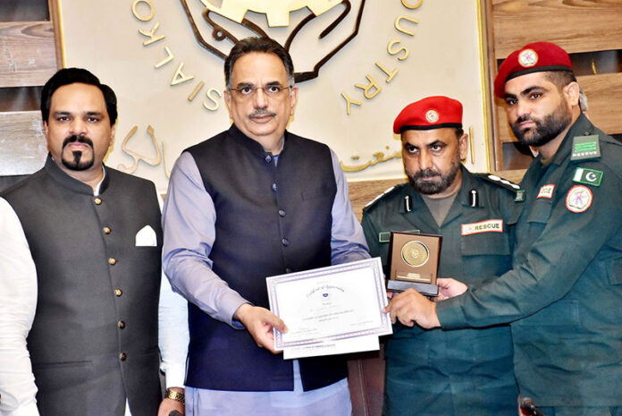 Group photo of President Chamber of Commerce Abdul Ghafoor Malik, Syed Kamal Abid Divisional Emergency Officer presenting awards to the Rescue 1122 officers