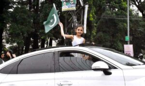 A girl proudly shows her love for her motherland by hoisting the national flag on a moving car.