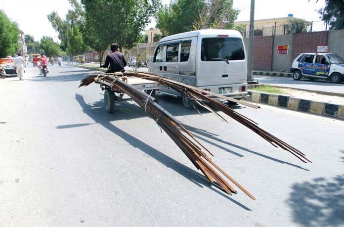 Iron rods loaded onto a motorcycle loader for a construction project are being transported through the city without safety precautions, raising concerns about potential accidents