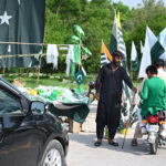 Commuters purchasing national flag displayed by the roadside vendors as the nation celebrates the Independence Day of Pakistan