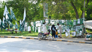Commuters purchasing national flag displayed by the roadside vendors as the nation celebrates the Independence Day of Pakistan