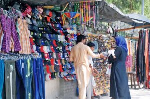 A family picks out a colorful hat for their child to protect form heatwave at roadside stall.