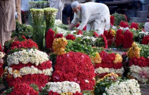 A labourer transports bundles of flowers to vendors at a wholesale flower market in the provincial capital.